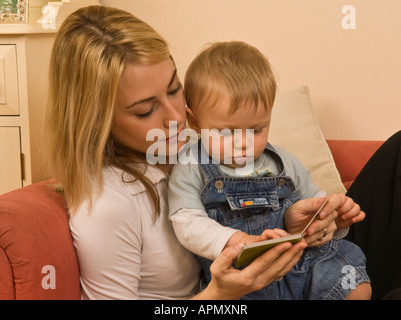 Madre che legge un libro al bambino in grembo di dieci mesi Foto Stock