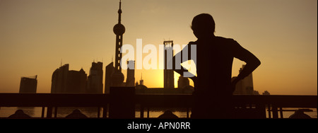 Albe su skyline come uomo anziano esercizi tai chi, il Bund, Shanghai, Cina Foto Stock