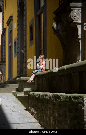 Piccolo Ragazzo si siede tranquillamente da solo su una parete in Toscana