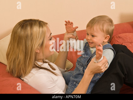 Madre che affronta il bimbo in grembo che si tiene per mano ridendo, giocando a applaudire, felice, di dieci mesi Foto Stock