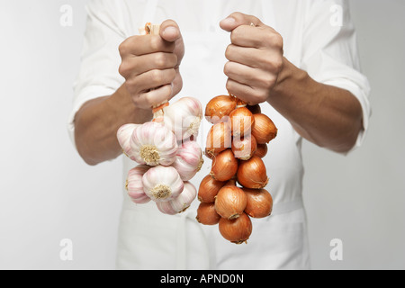 Lo Chef holding mazzetto di aglio e scalogno cipolle (metà sezione) Foto Stock