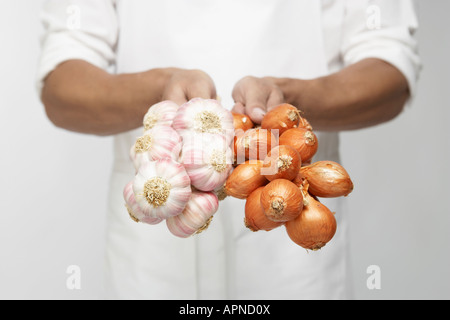 Lo Chef holding mazzetto di aglio e scalogno cipolle (metà sezione) Foto Stock