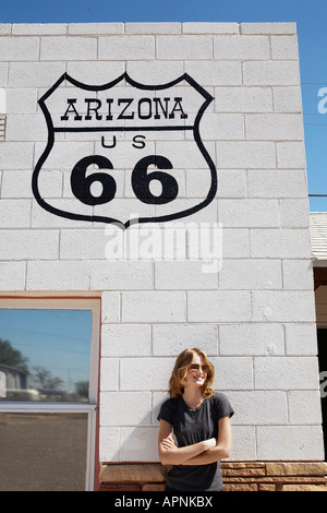 Giovane donna in piedi al di sotto di Route 66 segno Foto Stock