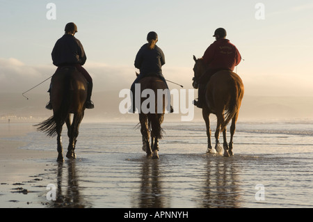 Vista posteriore di tre persone a cavallo sulla spiaggia Ynyslas Borth Ceredigion West Wales gennaio pomeriggio Foto Stock
