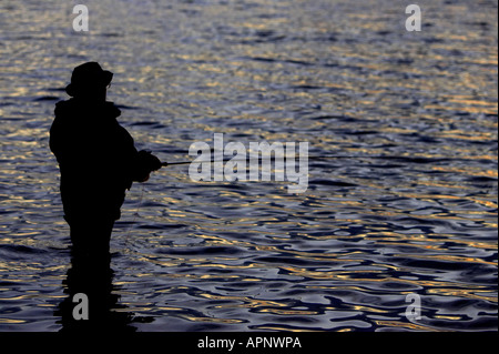 Pescatore di Pesca a Mosca Report di Pesca sul serbatoio Stoneyford al tramonto nella contea di Antrim Irlanda del Nord Foto Stock