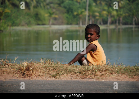 Un ragazzo ubicazione in banca del lago vellayani kerala. Foto Stock