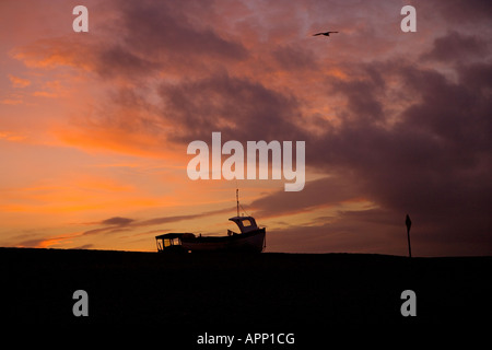 Barca da pesca stagliano contro un tramonto a Weybourne Beach, Norfolk, Regno Unito Foto Stock