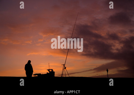 Fisherman stagliano contro un tramonto a Weybourne Beach, Norfolk, Regno Unito Foto Stock