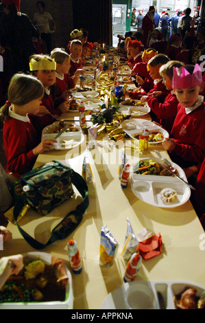 Scuola cena di Natale inglese british boy di istruzione per i cappelli di carta mangiare mangiare la Turchia pasto pranzo kids bambini cibo divisa rossa p Foto Stock