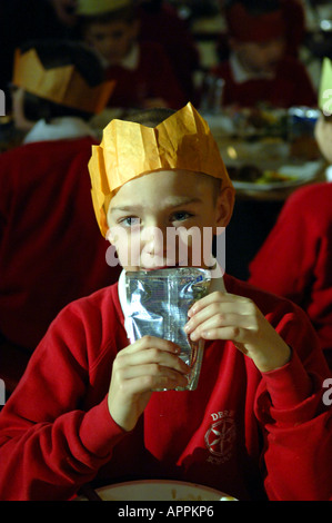 Scuola cena di Natale inglese british boy di istruzione per i cappelli di carta mangiare mangiare la Turchia pasto pranzo kids bambini cibo divisa rossa p Foto Stock