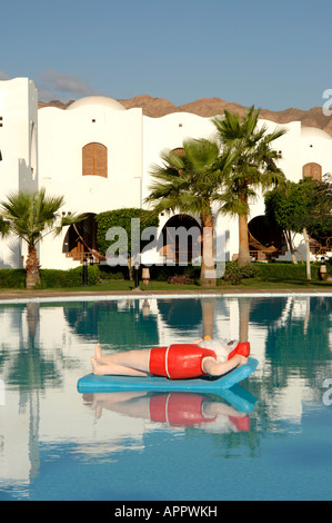 Babbo Natale sorseggiando un cocktail su un lilo in una piscina. Foto Stock