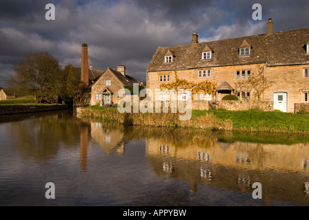 Fila di Cotswold cottage e mulino ad acqua Museum si riflette nel fiume occhio, Lower Slaughter, Cotswolds, Gloucestershire, Regno Unito Foto Stock