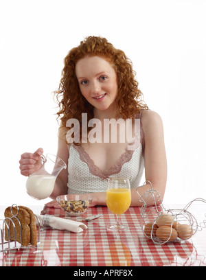 Giovane donna seduta al tavolo per la colazione di frutta e dado muesli con latte toast integrale uova sode succo di arancia Foto Stock