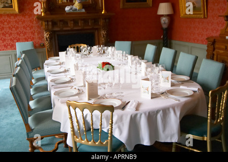 Il classico lussuosa sala da pranzo in stile antico impostato per una cena di gala con starched tovaglioli e tavolo bianco panno e molti bicchieri per la degustazione di champagne come visto attraverso la porta di ingresso le rose decorare la tavola e i menu a Champagne Deutz in Ay, Vallée de la Marne, Champagne, Marne, Ardenne, Francia, bassa luce grano sgranate Foto Stock