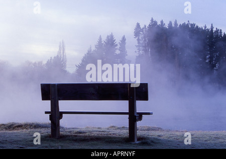 Bench in morning mist over the Clutha River at Albert Town South Island New Zealand Foto Stock