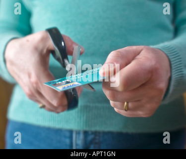 In prossimità delle mani femminili il taglio di una carta di credito con un paio di forbici Foto Stock