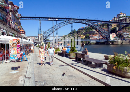 I turisti e i locali a prendere il sole lungo il fiume Douro bank vicino al D. Luiz I Bridge a Porto, Portogallo. Patrimonio Mondiale dell'Unesco. Foto Stock