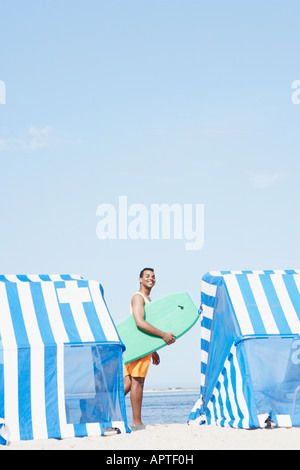 Uomo ispanico holding boogie board presso la spiaggia Foto Stock