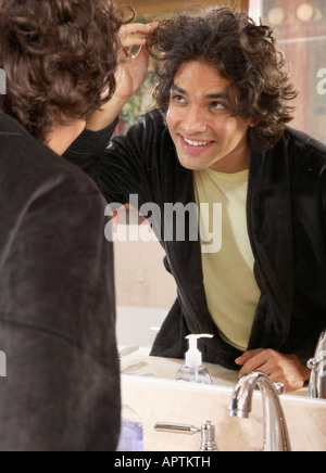 Uomo ispanico guardando nello specchio del bagno Foto Stock