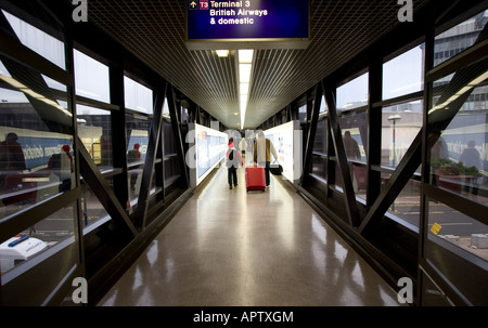 Passeggeri a piedi verso il basso e verso la porta d'imbarco del terminal 3 dell'Aeroporto Internazionale di Manchester a Manchester REGNO UNITO Foto Stock
