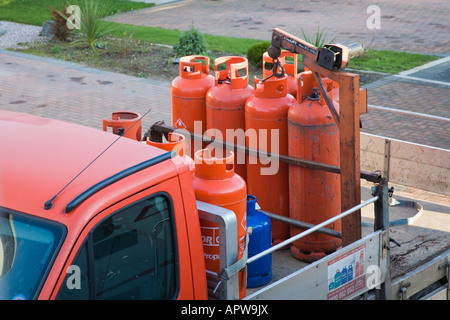 Regno Unito domestico rosso propano Calor Gas cilindri essendo consegnati sul carrello Foto Stock