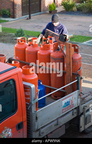 Regno Unito uomo offrendo grande rosso propano domestico Calor Gas cilindri sul carrello dal di sopra Foto Stock