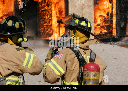 Due americani dei vigili del fuoco a discutere il loro piano di attacco su una struttura fire Foto Stock