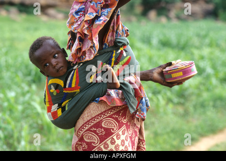 Giovane donna Peul indossando variopinti si avvolge con un bambino legato al suo indietro Foto Stock