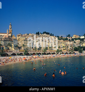 Affollata spiaggia con i bagnanti e persone lounging sotto colorati ombrelloni nella città vecchia di Mentone a sud della Francia Foto Stock