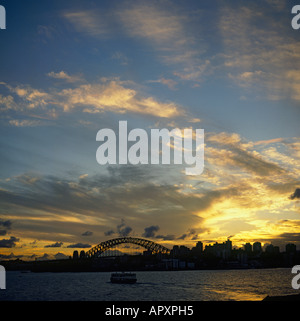 Fiery drammatico tramonto arancione striato di nuvole con il Ponte del Porto di Sydney e dello skyline della città in silhouette Sydney Australia Foto Stock