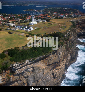Vista lungo strapiombo ripide scogliere oceaniche di Watsons con Macquarie faro sulla parte superiore e sul porto di Sydney al di là dell Australia Foto Stock