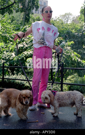 Donna con sprinkler dietro di lei il raffreddamento mentre si cammina per la sua épagneuls nel Central Park di New York City. Foto Stock