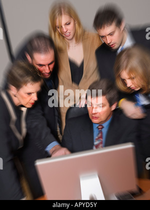 La gente di affari huddling intorno a un computer per discutere su questioni Foto Stock