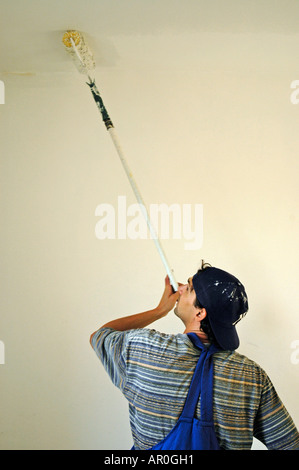 Casa pittore in abiti da lavoro è dipinto il soffitto bianco Foto Stock