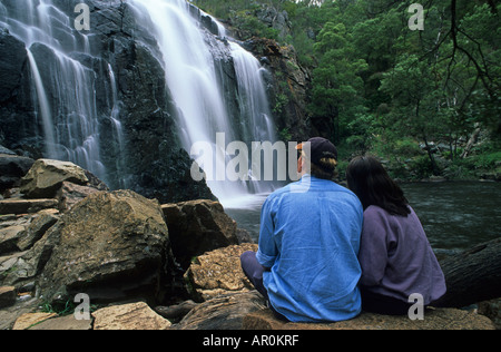 Matura la visione di Mackenzie Falls, Grampian NP, Australia, Victoria, Parco Nazionale di Grampians, coppia giovane da dietro, seduta wa Foto Stock