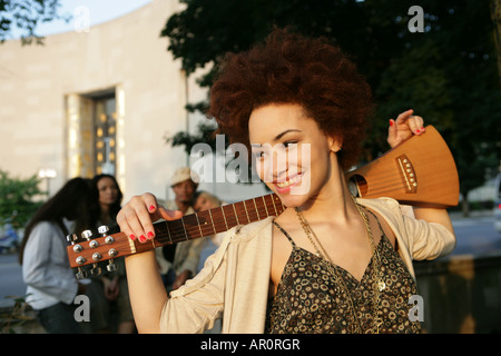 African American donna azienda uno strumento musicale sorridente Foto Stock