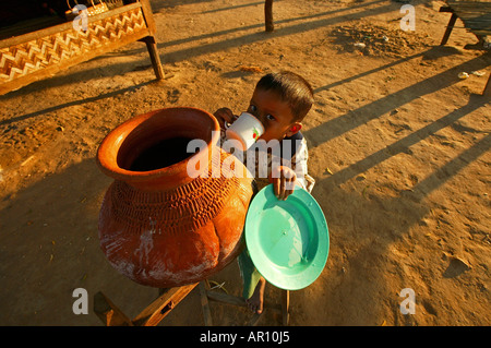 Piccolo bambino beve acqua dal vaso, birmania, myanmar Foto Stock