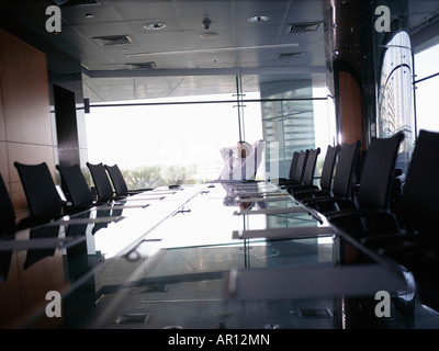 Imprenditore seduto da solo in un vuoto di sala conferenze Foto Stock