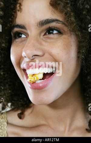 Donna sorridente con popcorn tra i suoi denti Foto Stock