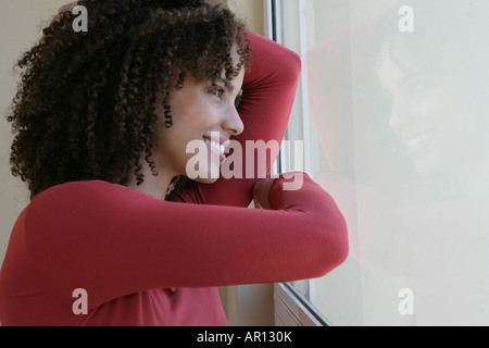 Donna appoggiata su un vetro di finestra Foto Stock