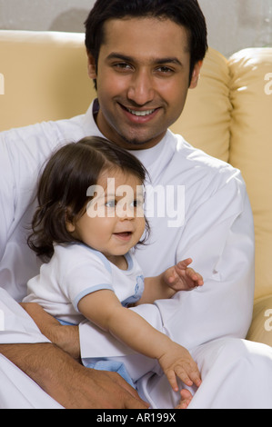 Padre tenendo il bambino nella stanza vivente Foto Stock