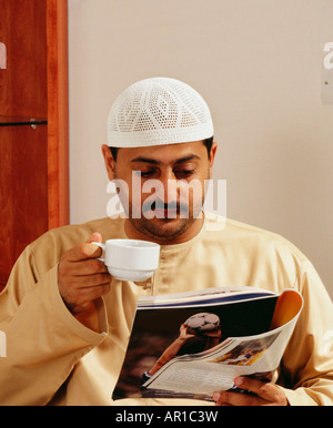 Un uomo maturo legge una rivista mentre avente una tazza di tè. Foto Stock