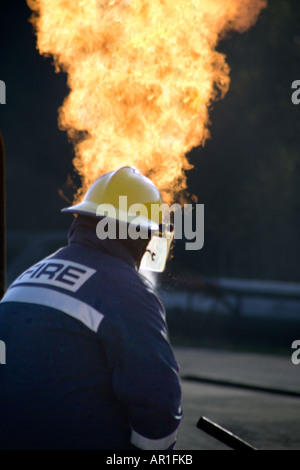 I vigili del fuoco facendo avanzare il fuoco dietro il tubo flessibile di acqua di protezione dello schermo Foto Stock