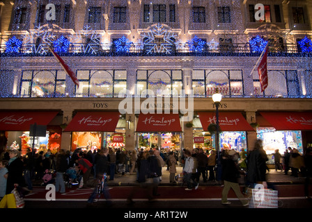 In orizzontale ampia angolazione della luci di Natale e gli amanti dello shopping a piedi lungo Regent Street fuori Hamleys negozio di giocattoli di Londra Foto Stock