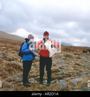 Una giovane coppia che guarda una mappa mentre cammina sulla brughiera sulle colline Gwynedd, Galles del Nord Regno Unito KATHY DEWITT Foto Stock