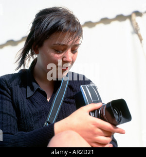 Una giovane studentessa di fotografia di fotografo femminile che usa guardare nel mirino di una fotocamera Hasselblad 500cm di formato medio Galles UK Foto Stock