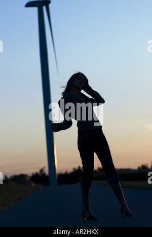Silhouette giovane donna in piedi su una strada con il mulino a vento Foto Stock