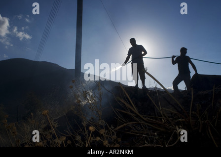 Residenti estinguere un incendio in una discarica durante gli incendi boschivi in estate 2007, Grecia, Peloponnes, Mani Skoutari Foto Stock