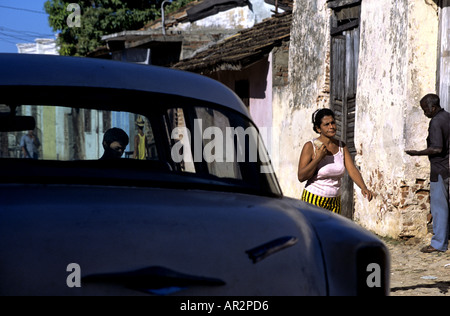 Donna in oro e nero a strisce a piedi in spandex past blue classic 50s auto in Trinidad, Cuba. Foto Stock