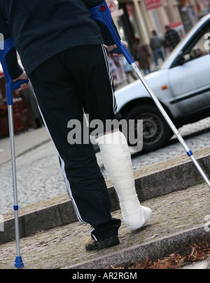 Uomo con due stampelle e una gamba in cast, Germania Foto Stock